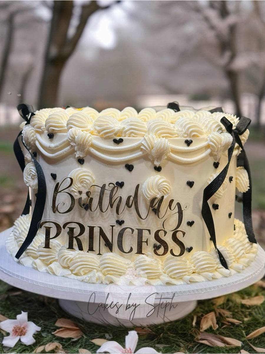 White piped cake with black bows and gold Birthday Princess lettering by Cakes by Steph, Leesburg VA