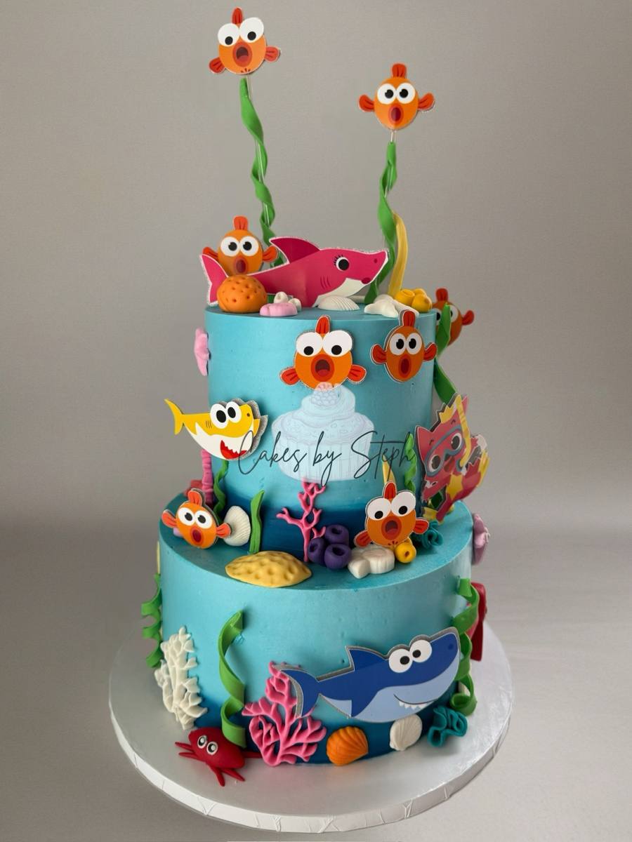 Two-tier blue ocean cake, Baby Shark and clownfish toppers by Cakes by Steph, Leesburg VA
