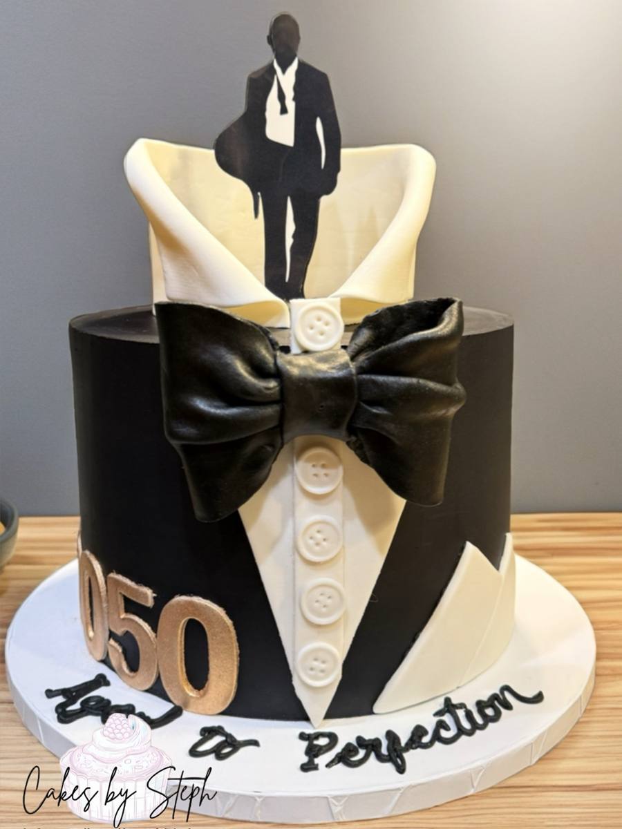 Two-tier black tuxedo cake with bow tie, "007 50, Aged to Perfection" by Cakes by Steph, Leesburg VA