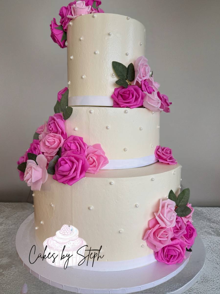 Pastel de boda blanco de tres pisos con rosas rosadas y perlas por Cakes by Steph