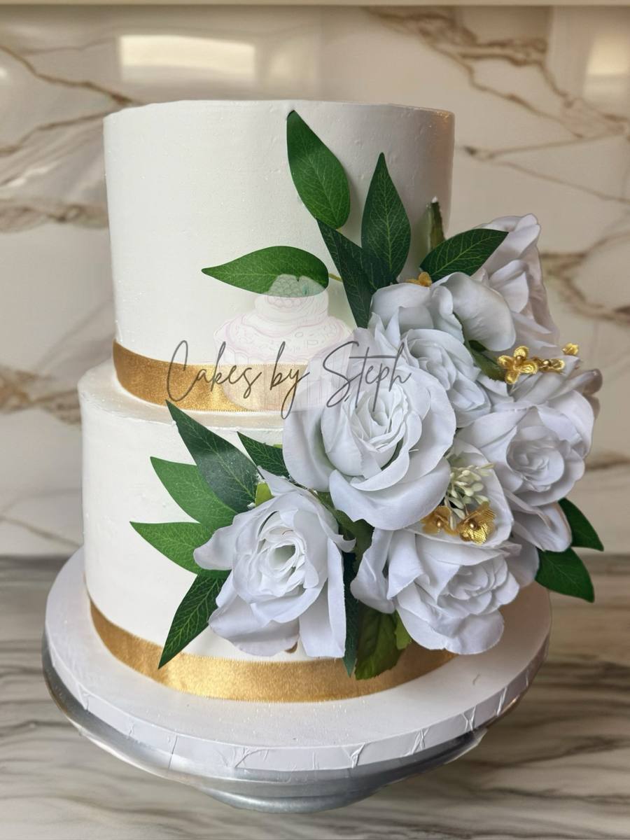 Pastel de boda blanco de dos pisos con cinta dorada y rosas por Cakes by Steph